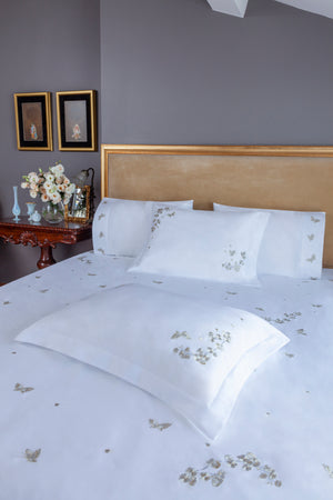 Butterfly Blossom Duvet Cover Set in white Egyptian cotton with butterfly embroidery – flanged shams and pillowcases on bed, styled in luxury bedroom.