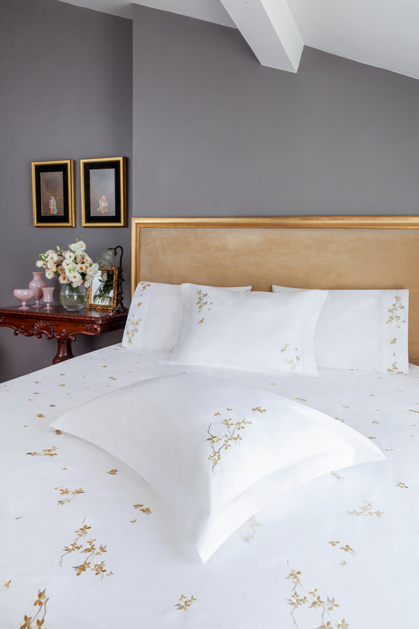 Cherry Blossom Duvet Cover Set in white Egyptian cotton with flower embroidery – flanged shams and pillowcases on bed, styled in luxury bedroom.