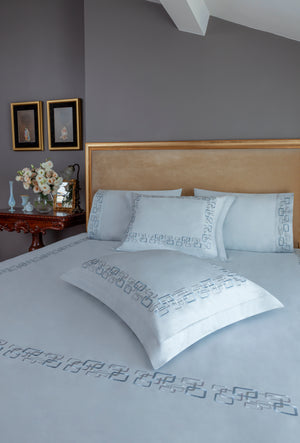 Geometric Duvet Cover Set in ice gray Egyptian cotton with geometric embroidery – flanged shams and pillowcases on bed, styled in luxury bedroom.