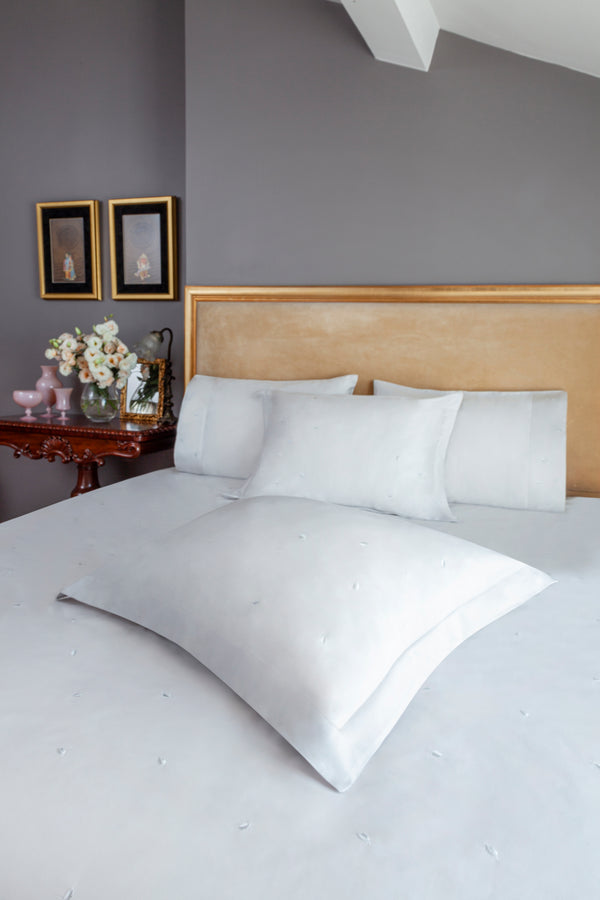 Mini Leaves Duvet Cover Set in white Egyptian cotton with small leaf embroidery – flanged shams and pillowcases on bed, styled in luxury bedroom.