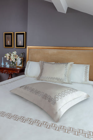 Versa Duvet Cover Set in ivory Egyptian cotton with geometric embroidery – flanged shams and pillowcases on bed, styled in luxury bedroom.