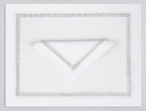White linen placemat and napkin set embroidered with gold and silver zig zag motif border, 100% European linen, handcrafted by Plein Soleil.