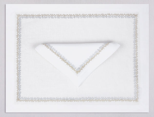 White linen placemat and napkin set embroidered with gold and silver zig zag motif border, 100% European linen, handcrafted by Plein Soleil.