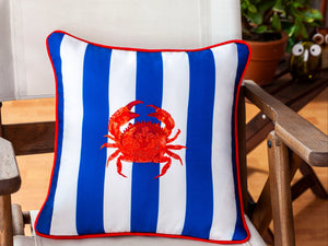 Decorative pillow with a red crab design on a striped background, placed on a chair indoors.