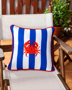 Decorative pillow with a red crab design on a striped background, placed on a chair indoors.
