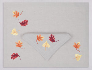 Light gray linen placemat and napkin set embroidered with red, orange, and yellow autumn leaves, 100% European linen, handcrafted by Plein Soleil.