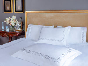 Ava Duvet Cover Set in white Egyptian cotton with elegant linked loop embroidery – flanged shams and pillowcases on bed, styled in luxury bedroom.