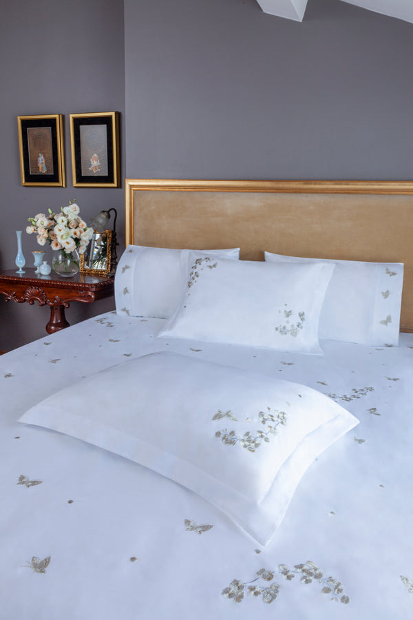 Butterfly Blossom Duvet Cover Set in white Egyptian cotton with butterfly embroidery – flanged shams and pillowcases on bed, styled in luxury bedroom.
