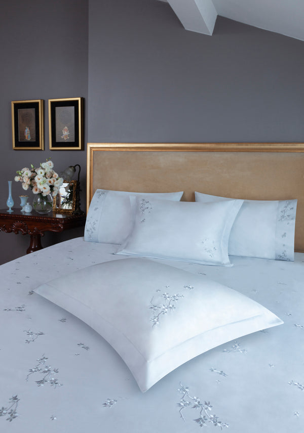 Cherry Blossom Duvet Cover Set in light gray Egyptian cotton with flower embroidery – flanged shams and pillowcases on bed, styled in luxury bedroom.