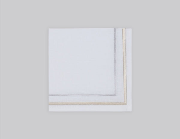 White linen cocktail napkin embroidered with gold and silver line motif border, 100% European linen, handcrafted by Plein Soleil.