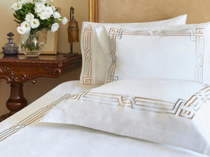 Deco Duvet Cover Set in white Egyptian cotton with Art Deco-inspired geometric embroidery – flanged shams and pillowcases on bed, styled in luxury bedroom.