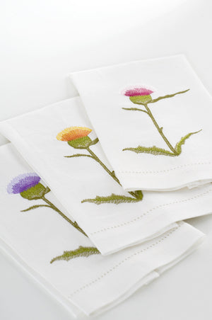 Set of white linen guest towels embroidered with purple, yellow, and pink thistle flowers – luxury floral bath linens by Plein Soleil.
