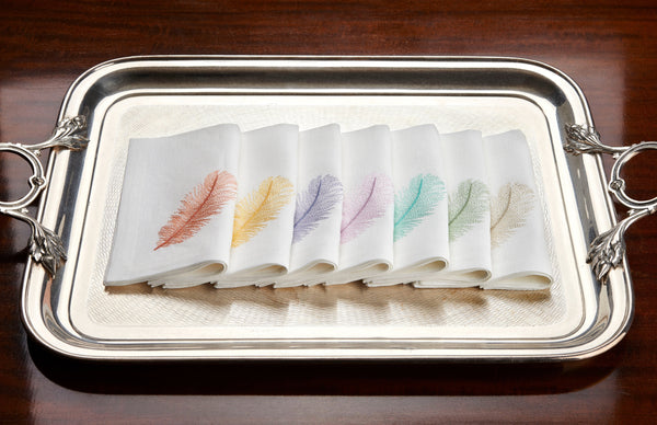 Silver tray with colorful feather designs on a wooden surface
