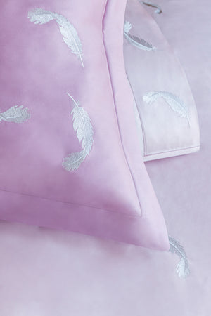 Detail of Feathers Duvet Cover Set – feather embroidered on light rose Egyptian cotton pillow shams and top sheet.