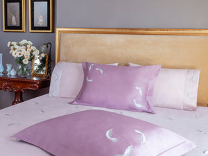 Feathers Duvet Cover Set in light rose Egyptian cotton with feather embroidery – flanged shams and pillowcases on bed, styled in luxury bedroom.