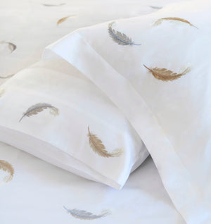 Detail of Feathers Duvet Cover Set – feather embroidered on white Egyptian cotton pillow shams and top sheet.