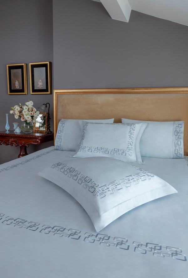 Geometric Duvet Cover Set in ice gray Egyptian cotton with geometric embroidery – flanged shams and pillowcases on bed, styled in luxury bedroom.