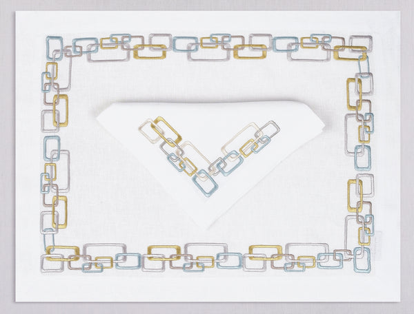 White linen placemat and napkin set embroidered with ice blue, gray, and gold geometric motif border, 100% European linen, handcrafted by Plein Soleil.