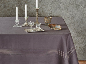 Table setting with a gray tablecloth, candles, and glassware against a textured wall.
