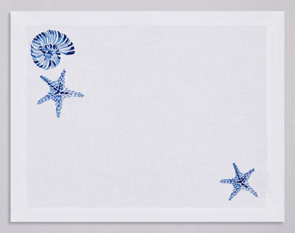 White linen placemat and napkin set embroidered with navy starfish and nautilus, 100% European linen, handcrafted by Plein Soleil.