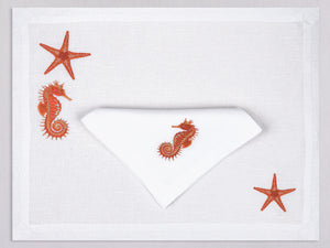 White linen placemat and napkin set embroidered with orange seahorse and starfish, 100% European linen, handcrafted by Plein Soleil.