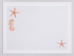 White linen placemat and napkin set embroidered with salmon colored seahorse and starfish, 100% European linen, handcrafted by Plein Soleil.