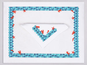 White linen placemat and napkin set embroidered with turquoise border and red sea animals, 100% European linen, handcrafted by Plein Soleil.