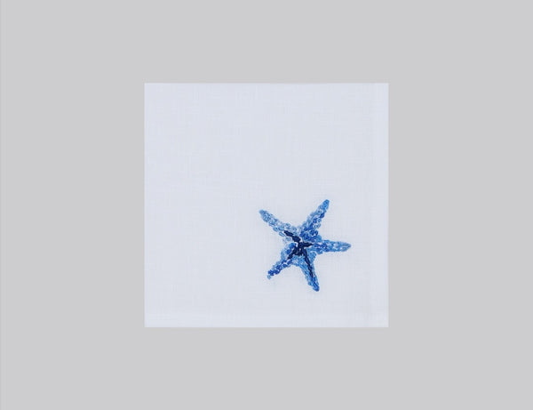 White linen cocktail napkin embroidered with blue starfish, 100% European linen, handcrafted by Plein Soleil.