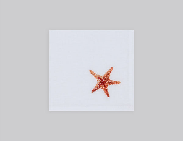 White linen cocktail napkin embroidered with orange starfish, 100% European linen, handcrafted by Plein Soleil.