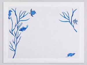 White linen placemat embroidered with blue fish and corals, 100% European linen, handcrafted by Plein Soleil.