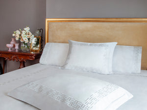 Versa Duvet Cover Set in white Egyptian cotton with geometric embroidery – flanged shams and pillowcases on bed, styled in luxury bedroom.
