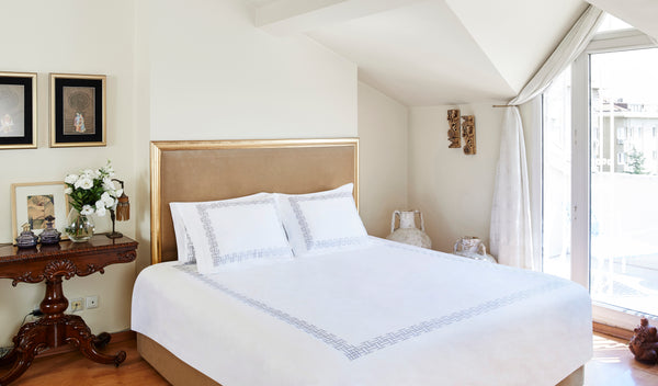 Versa Duvet Cover Set in white Egyptian cotton with geometric embroidery – flanged shams and pillowcases on bed, styled in luxury bedroom.