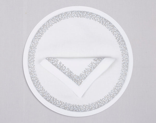 White round linen placemat and napkin set embroidered with silver waterfall motif border, 100% European linen, handcrafted by Plein Soleil.