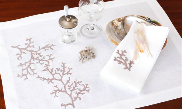 White placemats with coral patterns on a wooden table